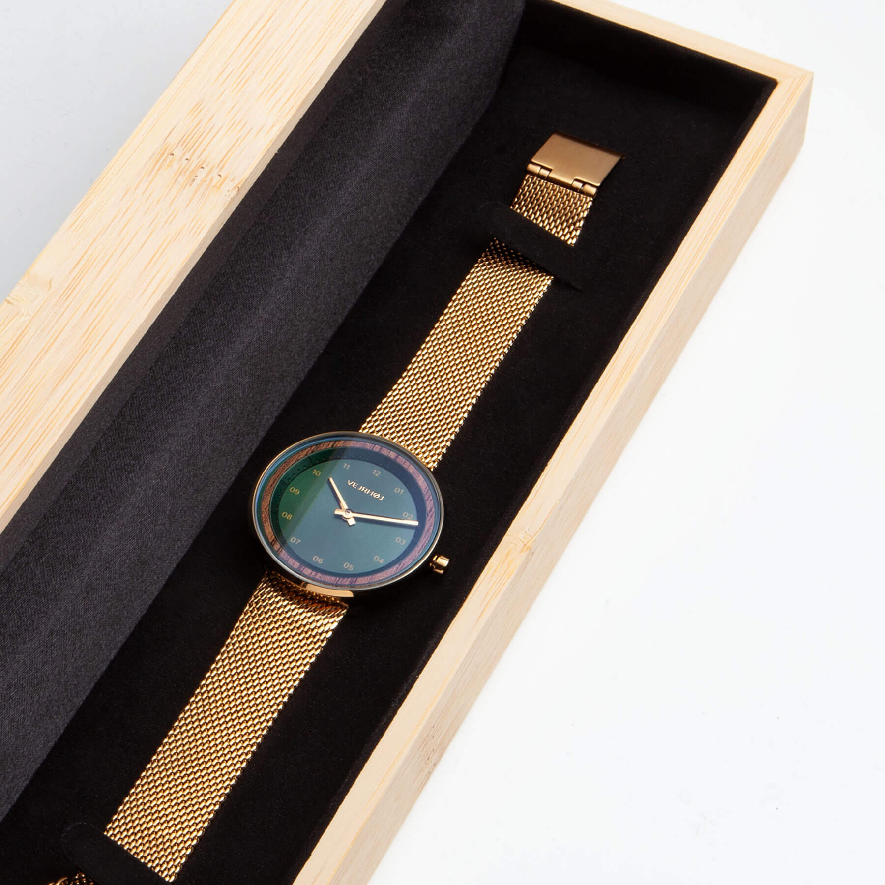 Green watch with golden casing with golden mesh band inside bamboo box