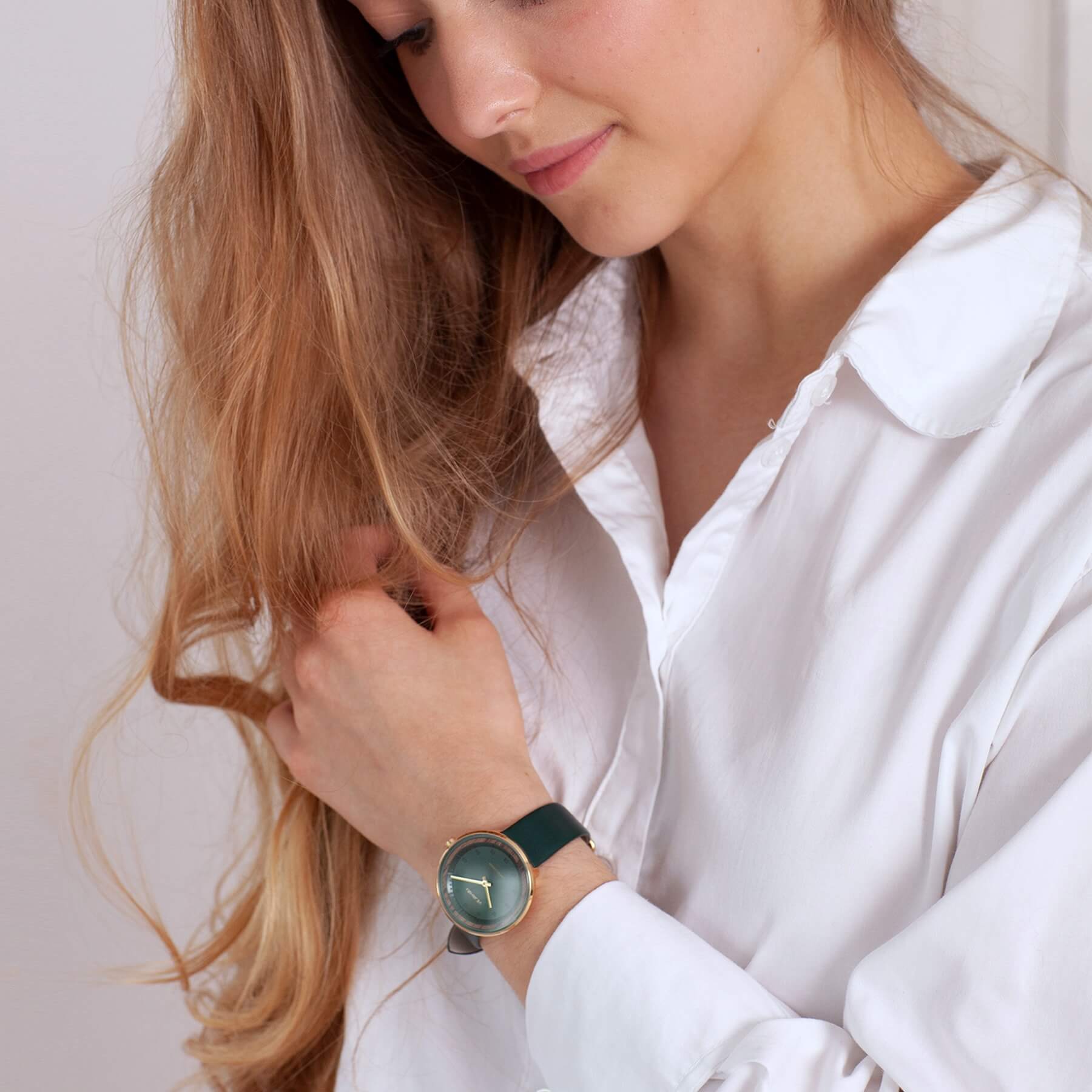 women long hair and a white shirt wearing a green and golden watch