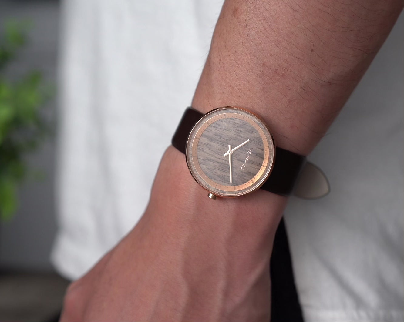 Man showcasing a simple wooden watch with walnut dial and rose gold casing