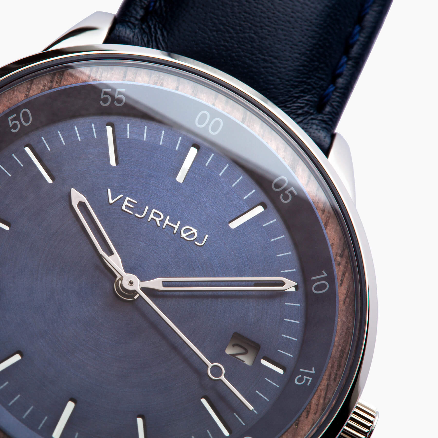 Closeup of an automatic watch with silver hands and a brused, blue dial