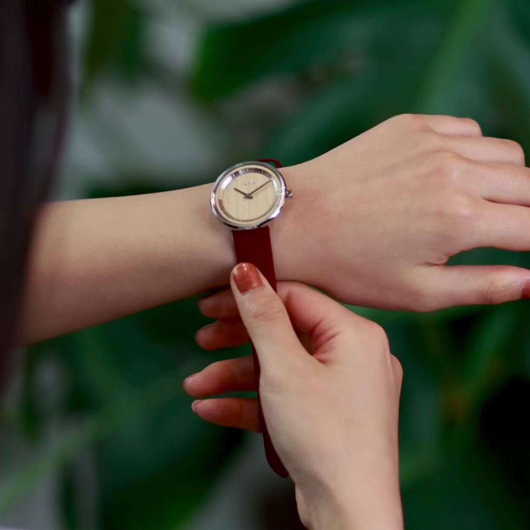 woman looking at wooden watch with steel casing and red straps