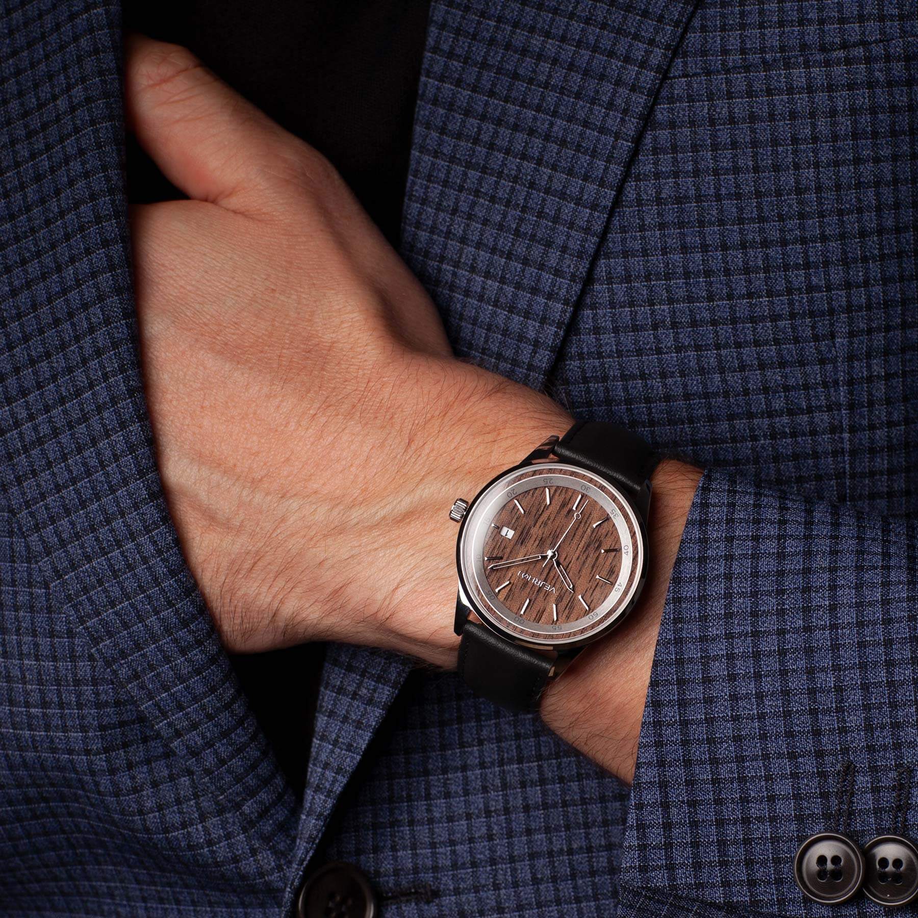 brown automatic wrist watch being worn with a blue suit