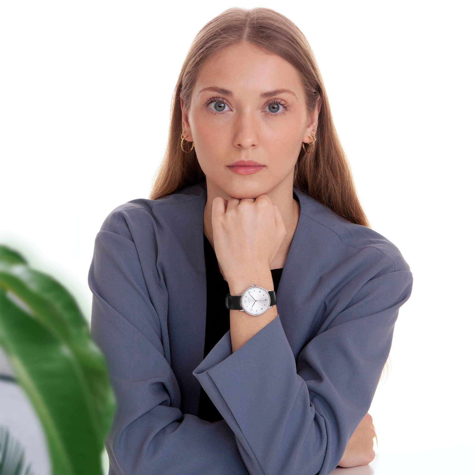 Woman wearing a blue blazer and Vejrhøj's Petite Royal silver with a plant in the background
