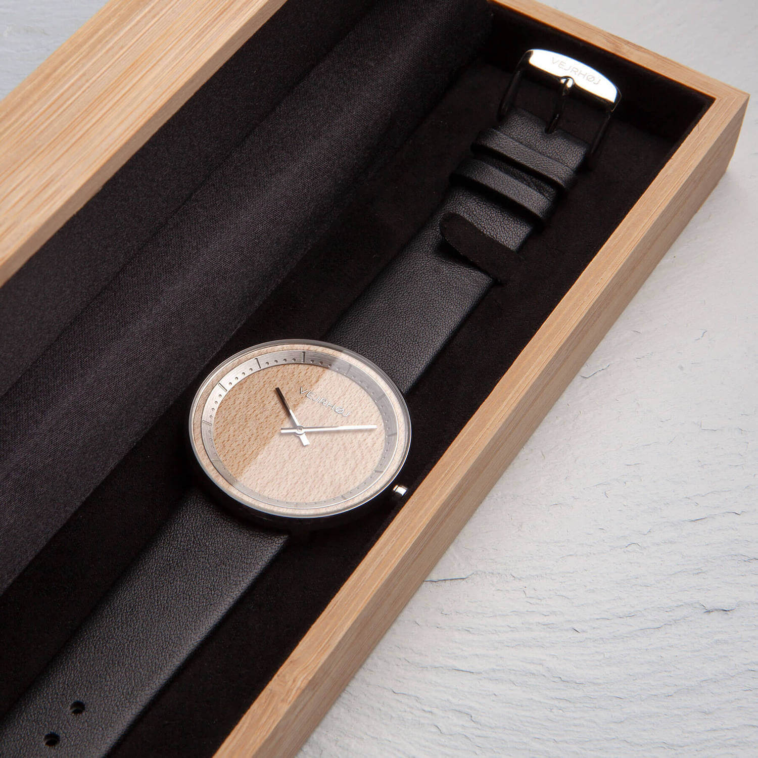 Wooden watch with black straps inside a bamboo box