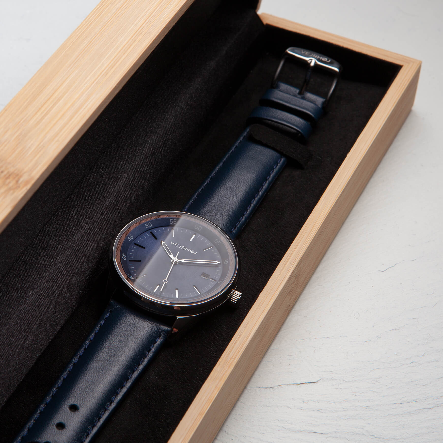 Blue automatic watch with silver hands and blue straps inside a beautiful wooden box